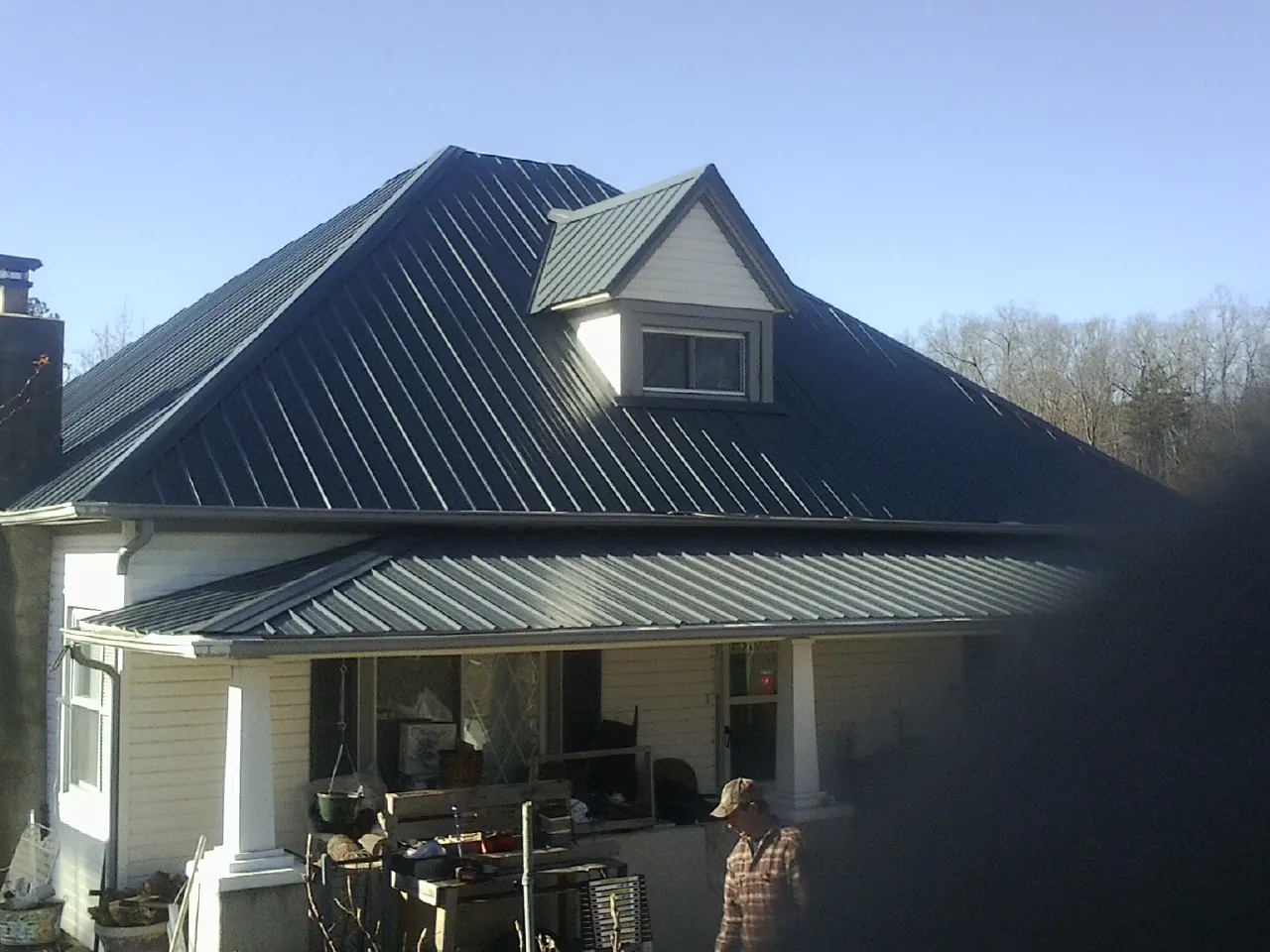 Dark blue standing seam metal roof with a dormer above a front porch in Wyoming