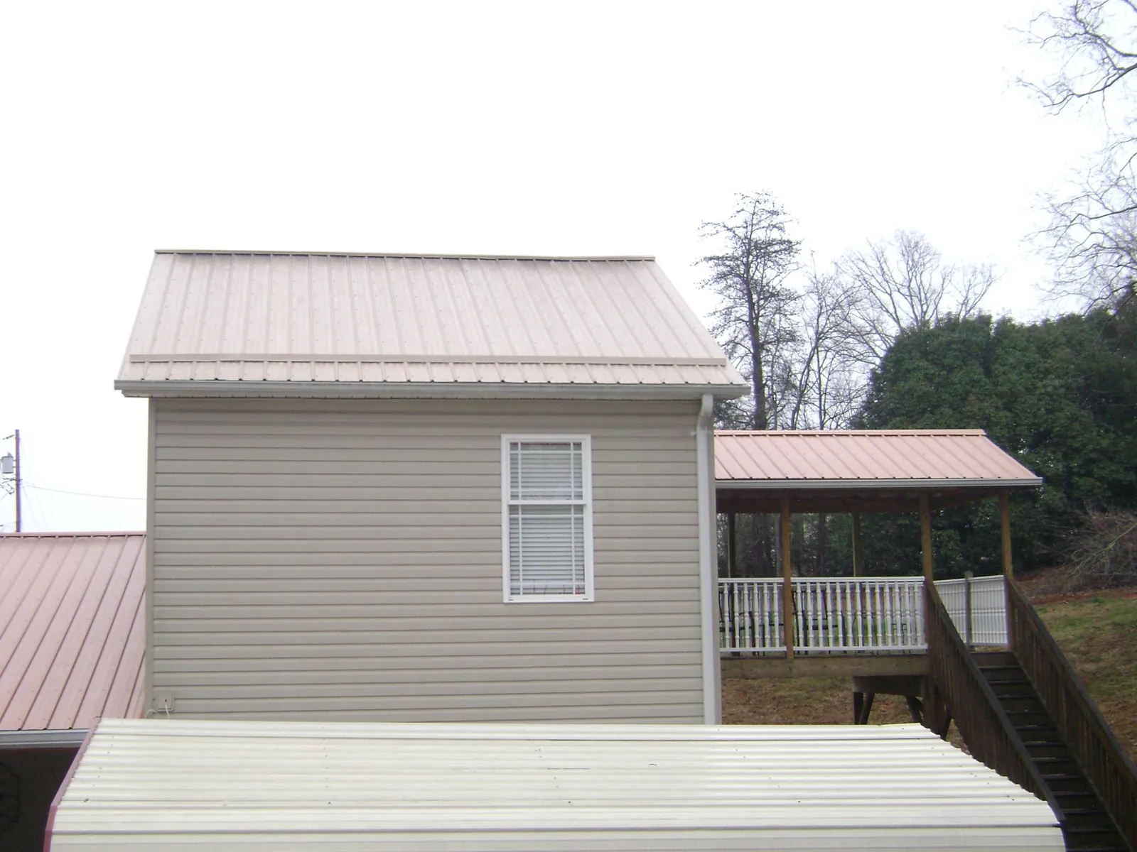 Tan metal roofs on a two story addition and attached porch, from a Roof Replacement job in Wyoming